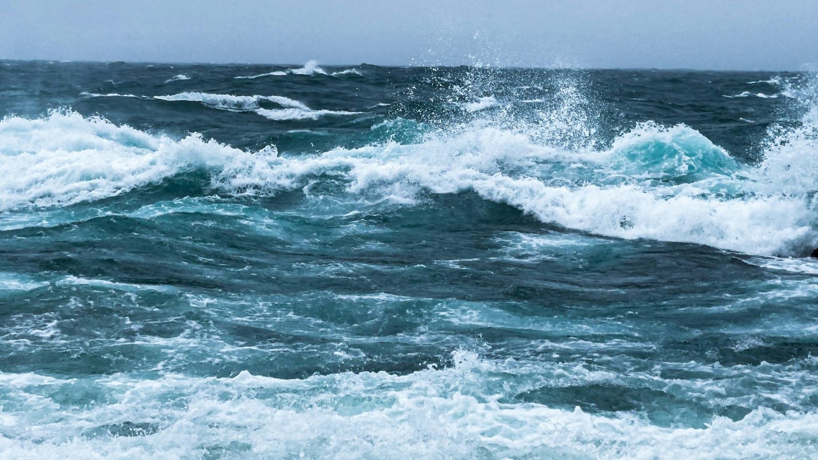 Olas rompiendo en la orilla bajo un cielo gris